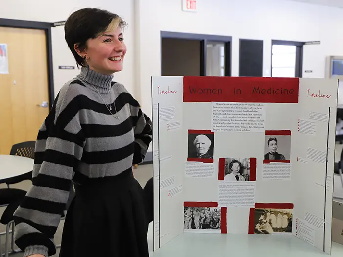 Student presents a 'Women in Medicine' research display.