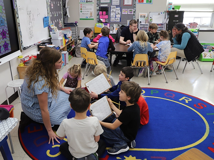 Teacher works with children in an elementary classroom during small-group activities. src=