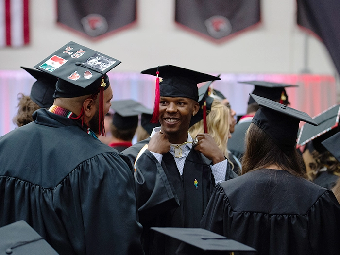 Graduates in caps and gowns talk before the ceremon