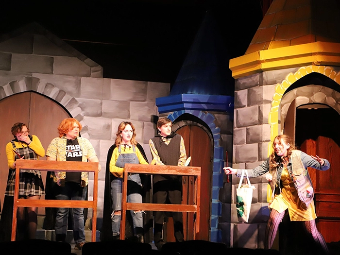 Students perform on stage against a colorful castle-themed set.